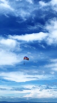 Two people fly on a parachute over a sky-blue sea on two domes towed by a boat. parasailing