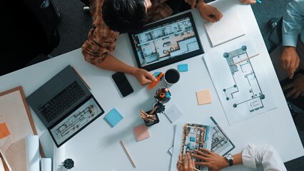 Architect team discussing and pointing and presenting blueprint to interior designer. Aerial view professional business people brainstorming building interior at table with house model. Alimentation.