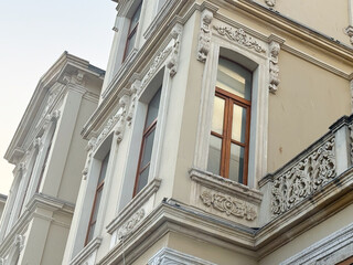 Obraz premium Ornate building facade with decorative stonework, large windows, and classical architectural details. Urban heritage, historical construction, and cultural architecture in cityscape.