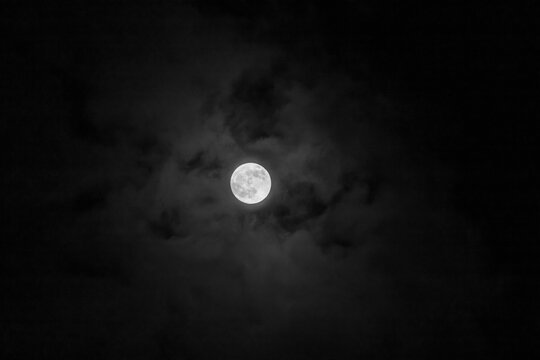 Full moon in the dark night sky with clouds, natural background.
