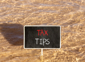 Naklejka premium Tax tips symbol. Concept word Tax tips on beautiful black blackboard. Beautiful Red sea water background. Black blackboard. Business tax tips concept. Copy space.