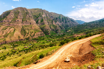 Russia, Dagestan, a wonderful landscape with the road passing near the mountain village, located in the decay of the foot of a huge steep mountain