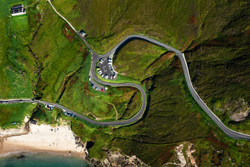 Aerial top down view of winding S shaped road and parking lot at Keem Beach on Achill Island in Ireland	