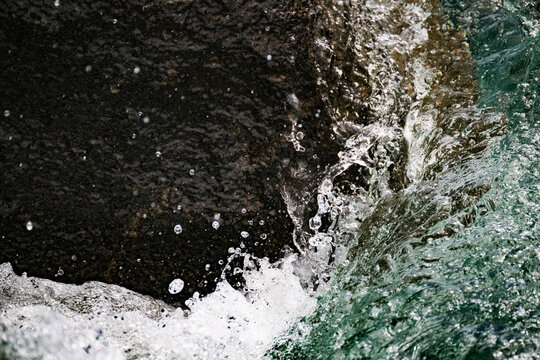 Closeup shot of water crashing up against a boulder