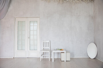 Chair, table and mirror in the interior of an white room with a door