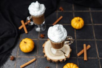 Warm autumn drinks with whipped cream and mini pumpkins on tiled surface