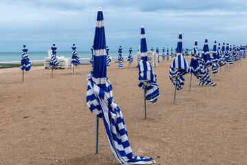 Alignement de parasols rayés bleus à Cabourg