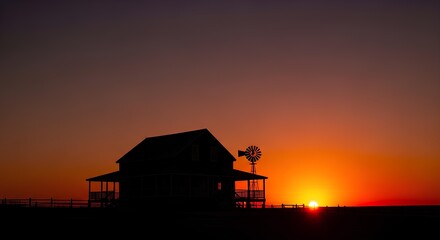Golden hour sunset over a remote country farmhouse, casting a peaceful silhouette against the vibrant orange sky