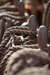 Coiled ropes secured on wooden belaying pins aboard traditional sailing ship. Nautical rigging and maritime craftsmanship. 
