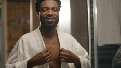 African American man wearing bathrobe shower naked male in bathroom hotel spa procedure looking at...