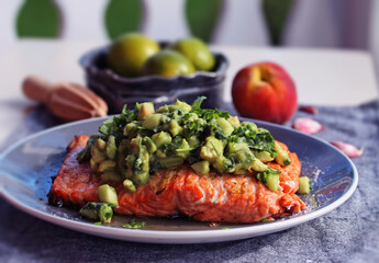 grilled salmon on a blue plate with avocado salad on top