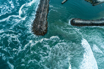 An aerial view of stone breakwaters in a rough and stormy sea The Eternal Battle of Human vs Nature