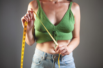 Close-up of slim woman measuring her waist with a tape measure