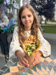 Obraz na płótnie Canvas Portrait of a beautiful 9 year old girl with long curly hair, sitting in a cafe outdoors
