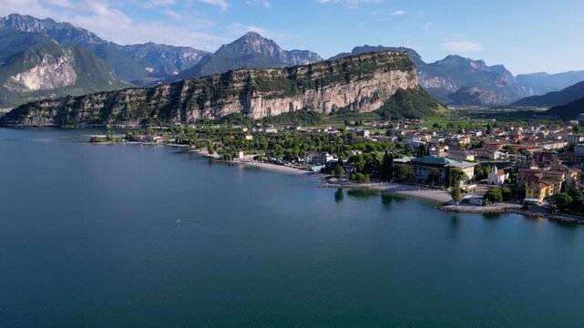 Stunning 4K aerial drone footage of Nago-Torbole and Torbole sul Garda on the northern shore of Lake Garda, Italy. Scenic view of the colorful town, mountains, beach, sailing boats