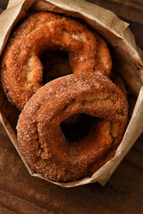 A brown paper bag filled with fresh baked Apple Cider Donuts.