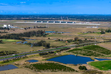 Fototapeta premium Drone aerial photograph of the new Western Sydney International Airport near agricultural farmland in the Greater Western Sydney suburb of Badgerys Creek in New South Wales, Australia. 