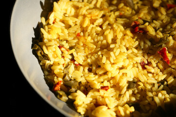 Cooked yellow rice with vegetables in bowl. Closeup of homemade meal in kitchen. Traditional food with peppers. Tasty hot dish in daylight. Culinary ingredient for lunch or dinner.
