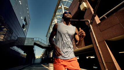 Athletic man running outdoors against the backdrop of modern urban architecture