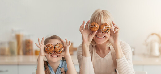 Kitchen Fun. Portrait of funny mature woman and little girl playing with food, making glasses of...
