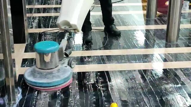 Professional janitor polishing shiny marble floor surface