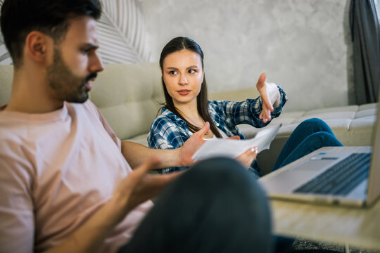 Stressed couple arguing over unpaid bills at home
