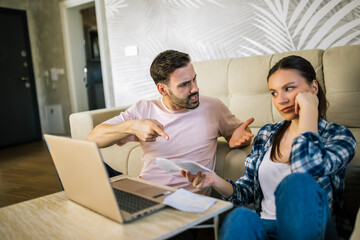 Stressed couple arguing over unpaid bills at home