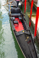 A traditional Venetian empty gondola stands at the pier in a narrow canal. © Ernest
