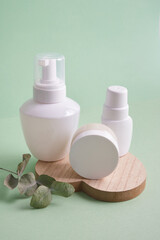various white bottles on pastel green background, cosmetic containers stand on wooden heart-shaped tray, natural products and self-care