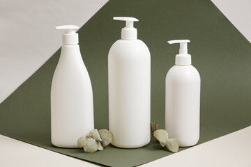 eucalyptus and three different white bottles without labels, containers for liquid soap or shampoo with dispenser,, mock up natural cosmetics product