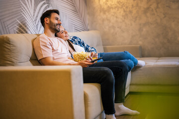 Happy couple hugging and watching TV at home