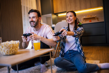 Young couple playing video games together at home