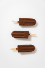 Chocolate ice cream popsicles on white background. Minimalist summer dessert concept