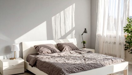 Sunlit bedroom with white furniture and gray bedding