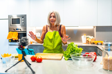 Senior woman filming cooking tutorial in modern kitchen