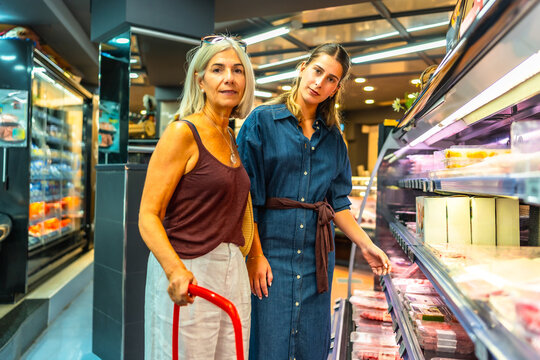 Women choosing meat products in refrigerated display case at supermarket