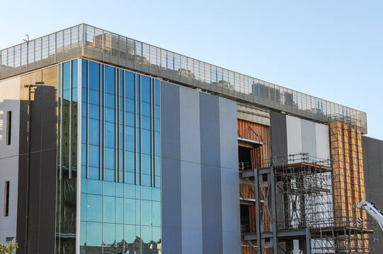 Exterior of a high-density data center campus under construction, showing glass panels, cooling infrastructure, scaffolding, and structural elements for advanced technology operations
