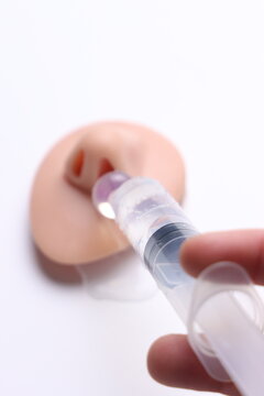 Close-up of hand holding syringe administering liquid into a nasal model