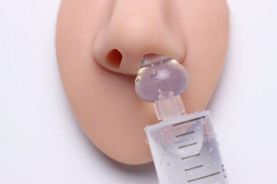 Close-up of hand holding syringe administering liquid into a nasal model
