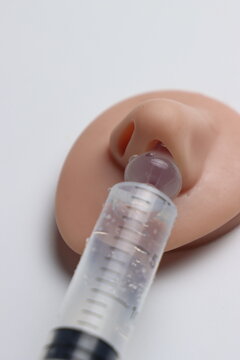 Close-up of hand holding syringe administering liquid into a nasal model