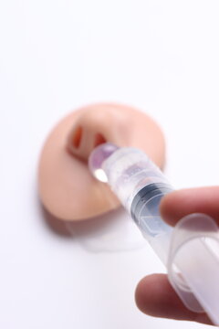 Close-up of hand holding syringe administering liquid into a nasal model