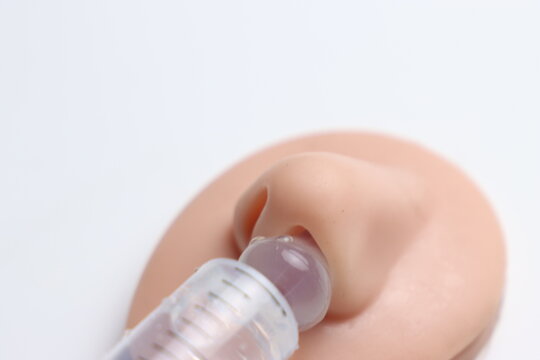 Close-up of hand holding syringe administering liquid into a nasal model