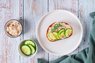 Cod liver, cucumber slices and arugula crostini on a plate on a table top view