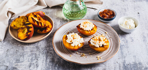 Grilled peach halves with ricotta and nuts on a plate on the table web banner
