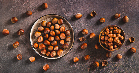 Nutritious unpeeled hazelnuts on a plate and peeled ones in a bowl top view web banner