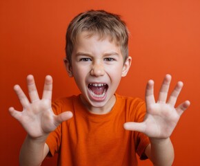A young boy with wide-eyed expression, mouth agape, displays a strong emotion, his hands outstretched, against a vibrant orange backdrop.