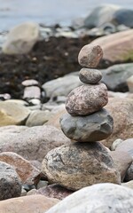 A realistic photograph of a seashore with stones and rocks stacked on top of each other like a small tower. 