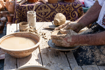An older potter shaping a clay pot