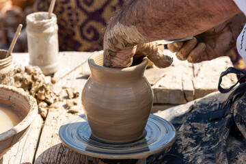 An older potter shaping a clay pot