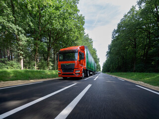 Orange truck with green trailer captured with motion blur effect showing movement and speed